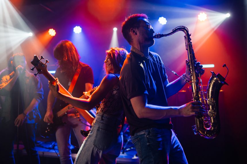 Musicians performing energetically with saxophone and guitar.